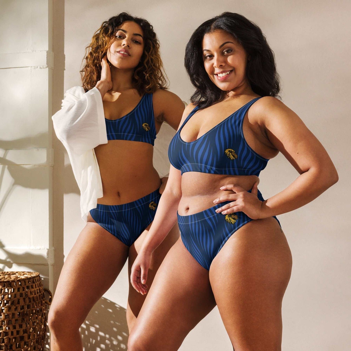 Two women wearing eco-friendly blue high-waisted bikinis with leaf designs, smiling indoors