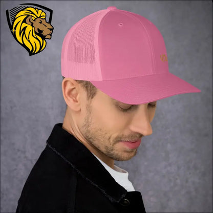 Bright pink trucker cap worn by a person showcasing bold style and gold embroidery