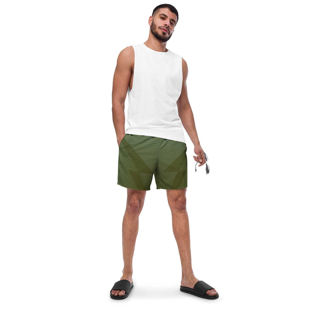 Man wearing eco-friendly green swim trunks with elastic waistband and drawcord, paired with a white sleeveless shirt and black slides.
