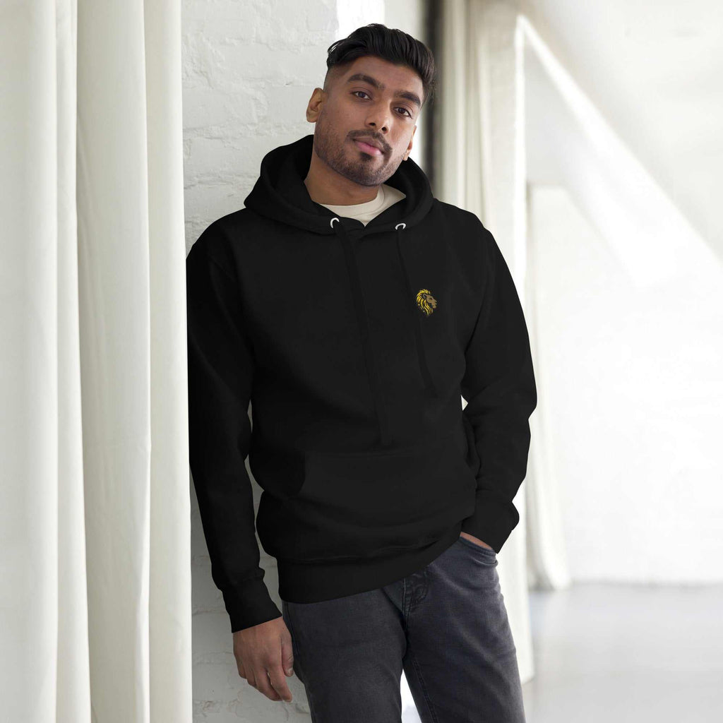 Man wearing black unisex essential hoodie with lion logo and front pouch pocket